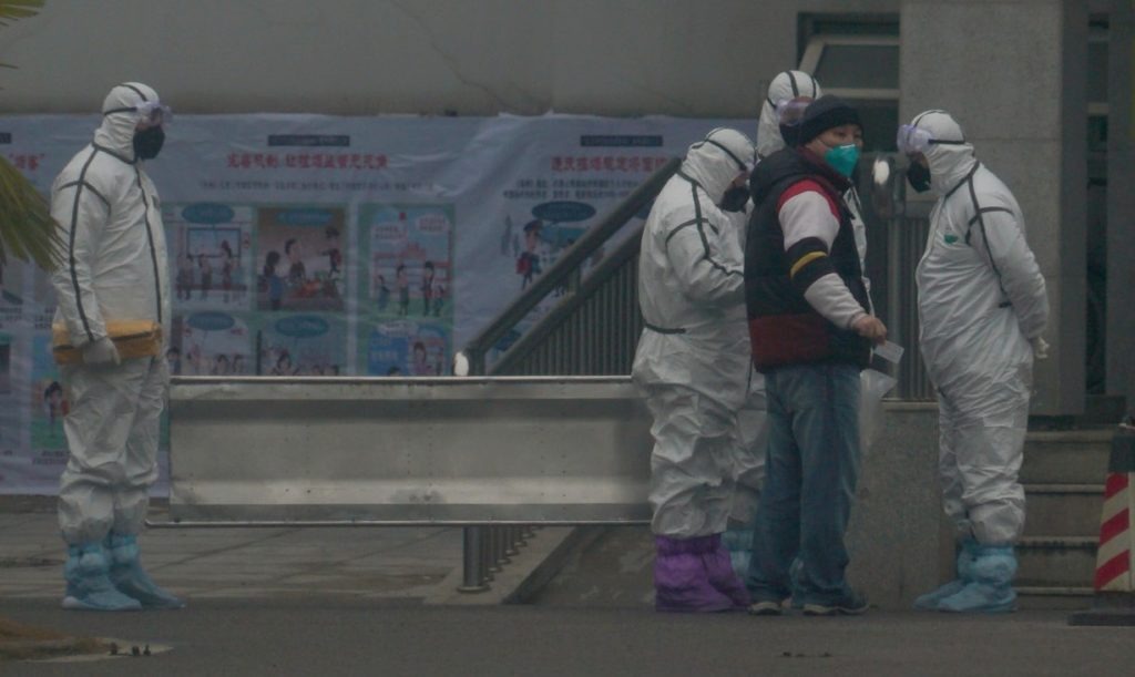 Staff in biohazard suits hold a metal stretcher on Tuesday by the inpatient department of Wuhan Medical Treatment Center, where some people infected with a novel coronavirus are being treated in China. CREDIT: Dake Kang/AP
