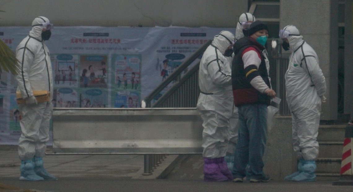 Staff in biohazard suits hold a metal stretcher on Tuesday by the inpatient department of Wuhan Medical Treatment Center, where some people infected with a novel coronavirus are being treated in China. CREDIT: Dake Kang/AP