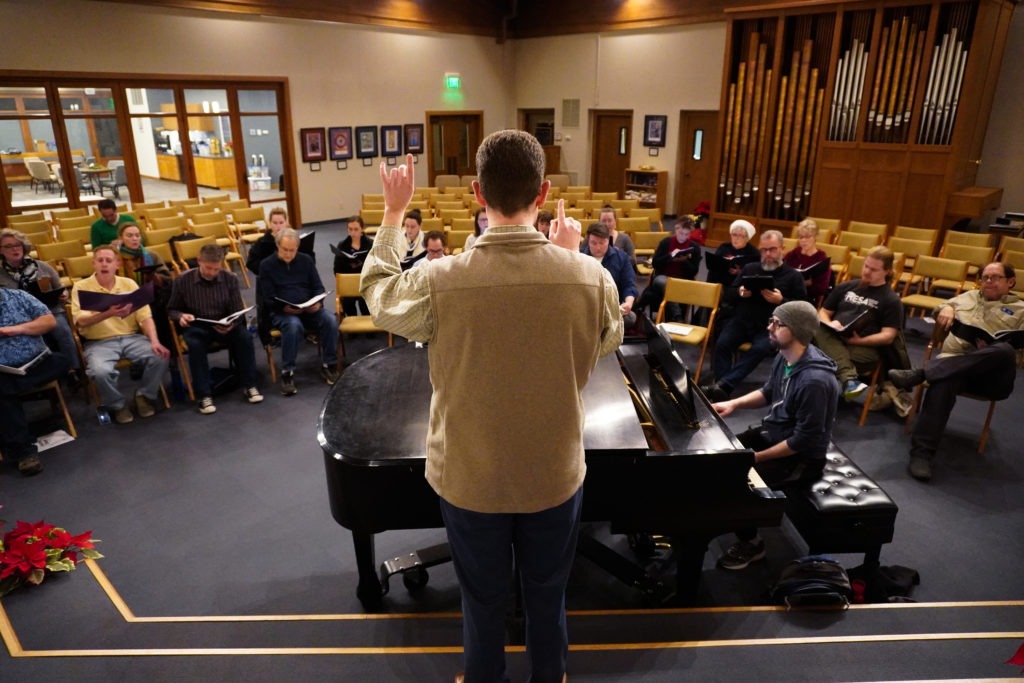 Mid-Columbia Mastersingers artistic director Justin Raffa directs the choir at a December 17 rehearsal at the Shalom United Church of Christ in Richland. CREDIT: Enrique Pérez de la Rosa/NWPB