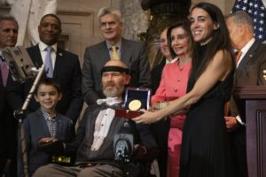 A Congressional Gold Medal is presented to amyotrophic lateral sclerosis (ALS) advocate and former National Football League (NFL) player, Steve Gleason, in Statuary Hall on Capitol Hill, Jan. 15, 2020. Holding the medal is his wife Michel Gleason. CREDIT: Manuel Balce Ceneta/AP