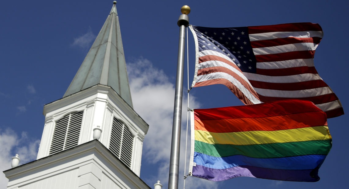 A Pride flag flies below the U.S. flag last year in front of the Asbury United Methodist Church in Prairie Village, Kan. Charlie Riedel/AP