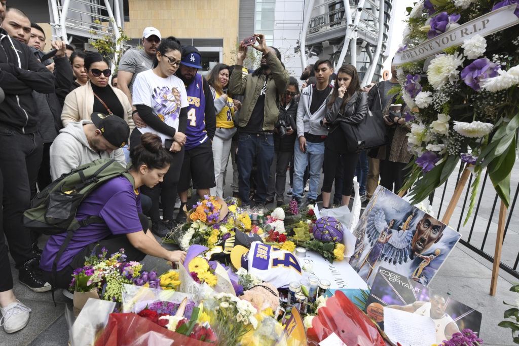 Valerie Samano, left, places flowers at a memorial near the Staples Center in Los Angeles, after the death of Laker legend Kobe Bryant on Sunday. CREDIT: Michael Owen Baker/AP