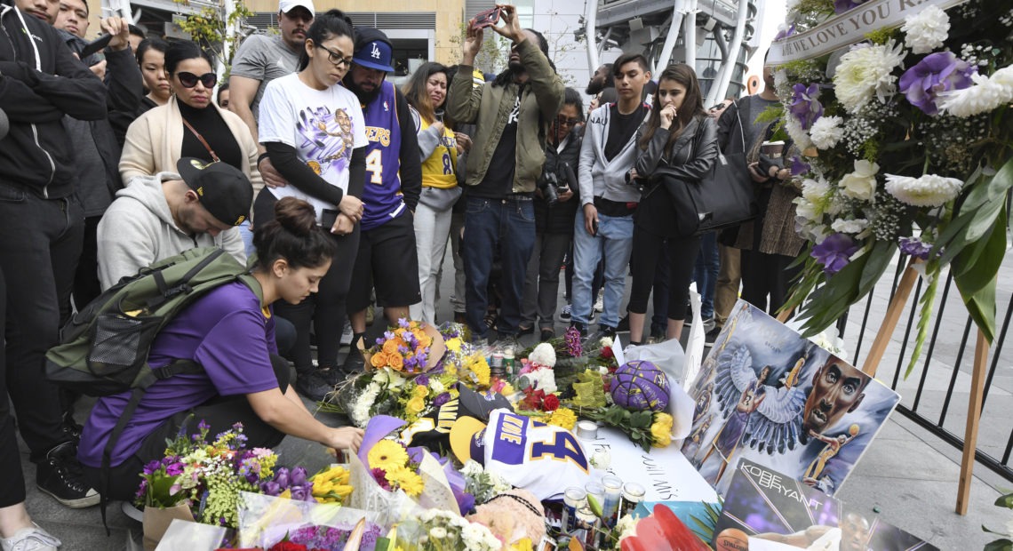 Valerie Samano, left, places flowers at a memorial near the Staples Center in Los Angeles, after the death of Laker legend Kobe Bryant on Sunday. CREDIT: Michael Owen Baker/AP
