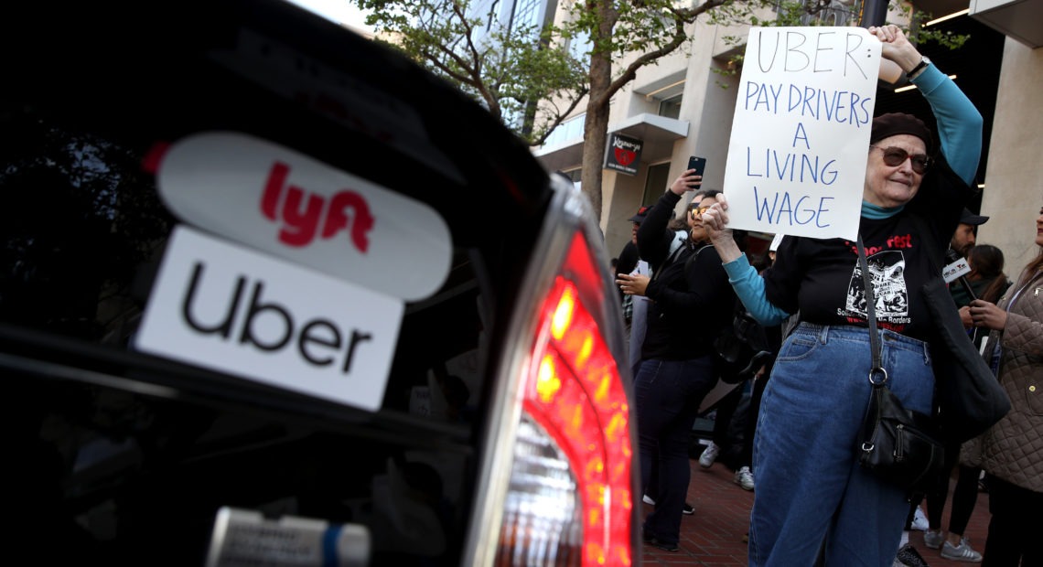A supporter of ride-hail drivers holds a sign during a protest in front of Uber headquarters on May 8 in San Francisco. A new law in California aims to change how gig economy and other contract workers are classified. CREDIT: Justin Sullivan Getty Images
