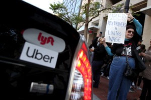 A supporter of ride-hail drivers holds a sign during a protest in front of Uber headquarters on May 8 in San Francisco. A new law in California aims to change how gig economy and other contract workers are classified. CREDIT: Justin Sullivan Getty Images