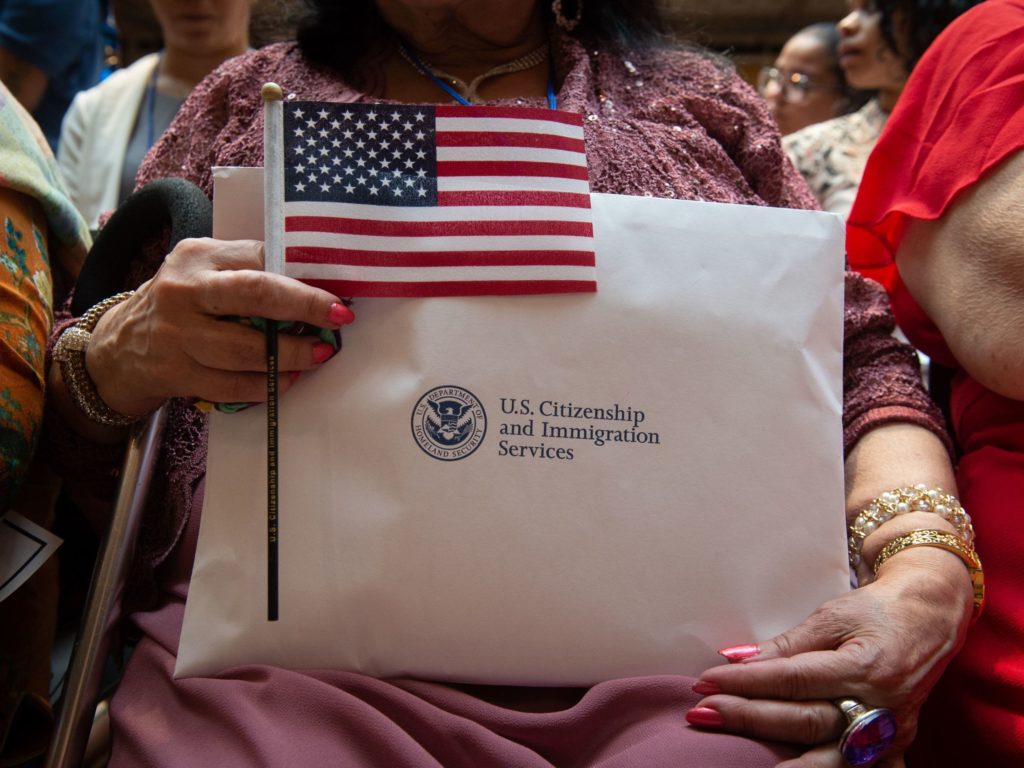 A newly sworn-in U.S. citizen holds the U.S. flag and paperwork during a 2018 naturalization ceremony in New York City. The Department of Homeland Security has agreed to share its records with the U.S. Census Bureau to help produce data about the U.S. citizenship status of every person living in the country, as ordered by President Trump. CREDIT: Bryan R. Smith/AFP via Getty Images