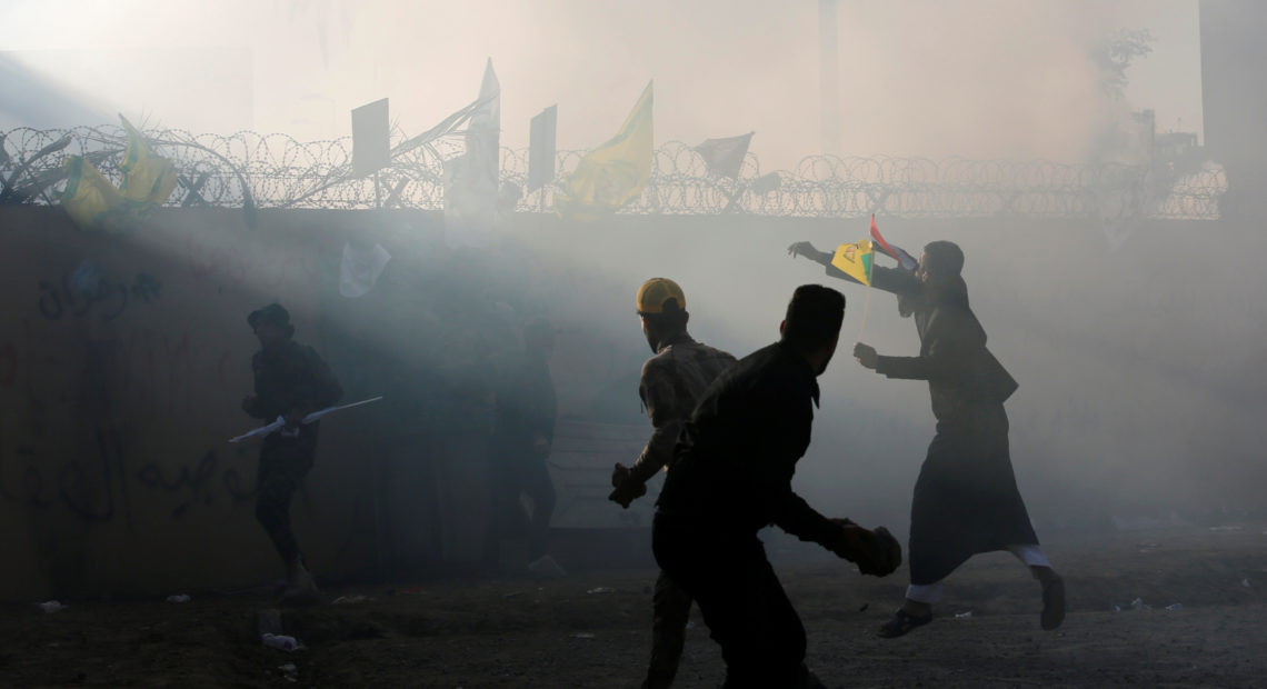 Protesters and militia members throw stones toward the U.S. Embassy in Baghdad on Tuesday. CREDIT: Wissm Al-Okili/Reuters