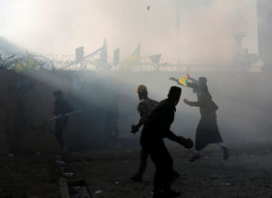 Protesters and militia members throw stones toward the U.S. Embassy in Baghdad on Tuesday. CREDIT: Wissm Al-Okili/Reuters