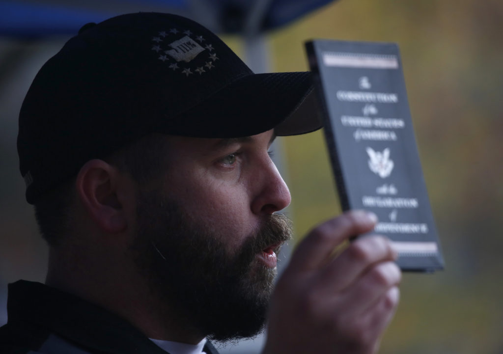 Matt Marshall, state leader of the Washington Three Percent, holds a copy of the U.S. Constitution during the United Against Hate rally. Jim Urquhart for NPR