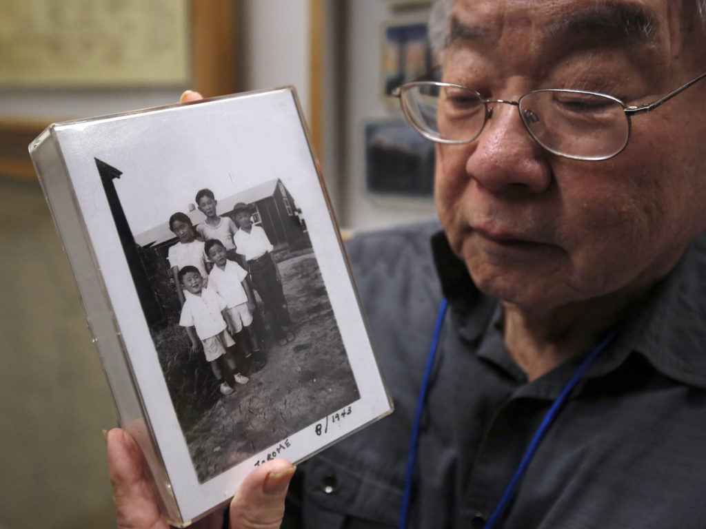 During a visit to the California Museum in Sacramento, Les Ouchida holds a 1943 photo of himself (front row center) and his siblings taken at the internment camp in Jerome, Ark., that his family was moved to from their home near Sacramento in 1942. CREDIT: Rich Pedroncelli/AP