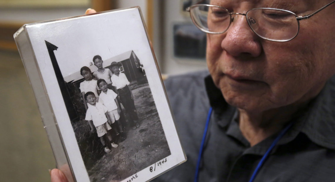 During a visit to the California Museum in Sacramento, Les Ouchida holds a 1943 photo of himself (front row center) and his siblings taken at the internment camp in Jerome, Ark., that his family was moved to from their home near Sacramento in 1942. CREDIT: Rich Pedroncelli/AP