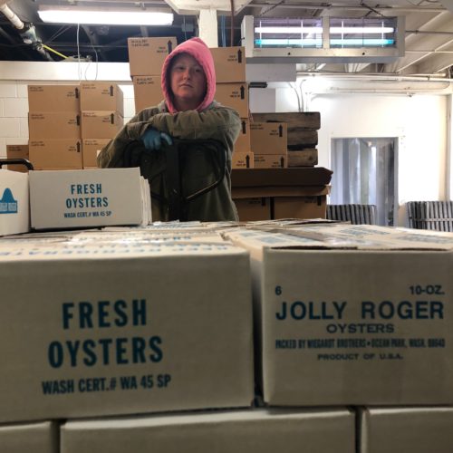 Amy Skillings of Oysterville, Washington, wheels the day's shucked oysters into a large cooler to await pickup. The oysters will be flown quickly across the country and to China.