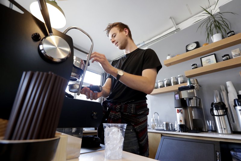 File photo. Porter Hahn makes an iced coffee drink in November 2019 in a Seattle coffee shop. U.S. services companies grew at a faster pace in February 2020 than the previous month. Then the coronavirus outbreak in the region shut down much of the service industry. CREDIT: Elaine Thompson/AP