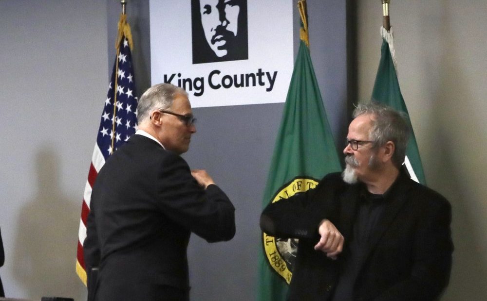 Washington Gov. Jay Inslee, left, gives an elbow touch to American Sign Language interpreter Terry Dockter after a news conference about the coronavirus outbreak Monday, March 16, 2020, in Seattle. Inslee ordered all bars, restaurants, entertainment and recreation facilities to temporarily close to fight the spread of COVID-19.