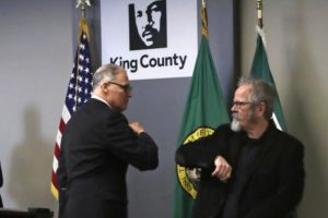 Washington Gov. Jay Inslee, left, gives an elbow touch to American Sign Language interpreter Terry Dockter after a news conference about the coronavirus outbreak Monday, March 16, 2020, in Seattle. Inslee ordered all bars, restaurants, entertainment and recreation facilities to temporarily close to fight the spread of COVID-19.