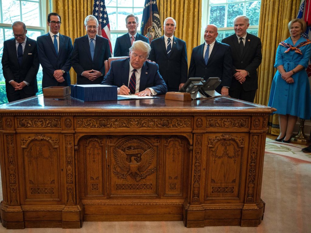 President Trump signs the CARES act, a $2 trillion rescue package to provide economic relief amid the coronavirus outbreak, at the Oval Office of the White House on Friday. Jim Watson/AFP via Getty Images