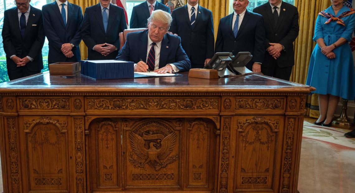 President Trump signs the CARES act, a $2 trillion rescue package to provide economic relief amid the coronavirus outbreak, at the Oval Office of the White House on Friday. Jim Watson/AFP via Getty Images