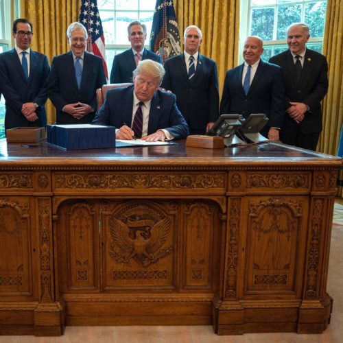President Trump signs the CARES act, a $2 trillion rescue package to provide economic relief amid the coronavirus outbreak, at the Oval Office of the White House on Friday. Jim Watson/AFP via Getty Images