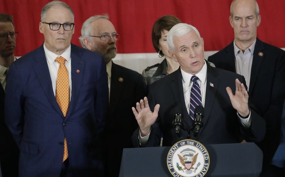 Vice President Mike Pence, at podium, speaks as Gov. Jay Inslee, left, and other officials look on during a news conference, March 5, 2020, at Camp Murray in Washington state. Pence was in the state to discuss the state's efforts to fight the spread of the COVID-19 coronavirus. CREDIT Ted S. Warren/AP