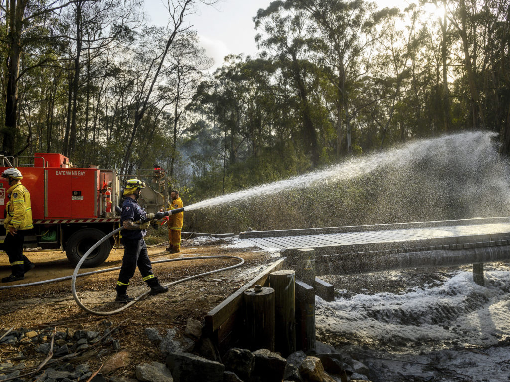 A firefighter coats a bridge with foam as a bushfire burns near Moruya, New South Wales, Australia, on Jan. 25. Wildfires destroyed more than 3,000 homes and razed more nearly 11 million hectares since the summer fires began. Noah Berger/AP