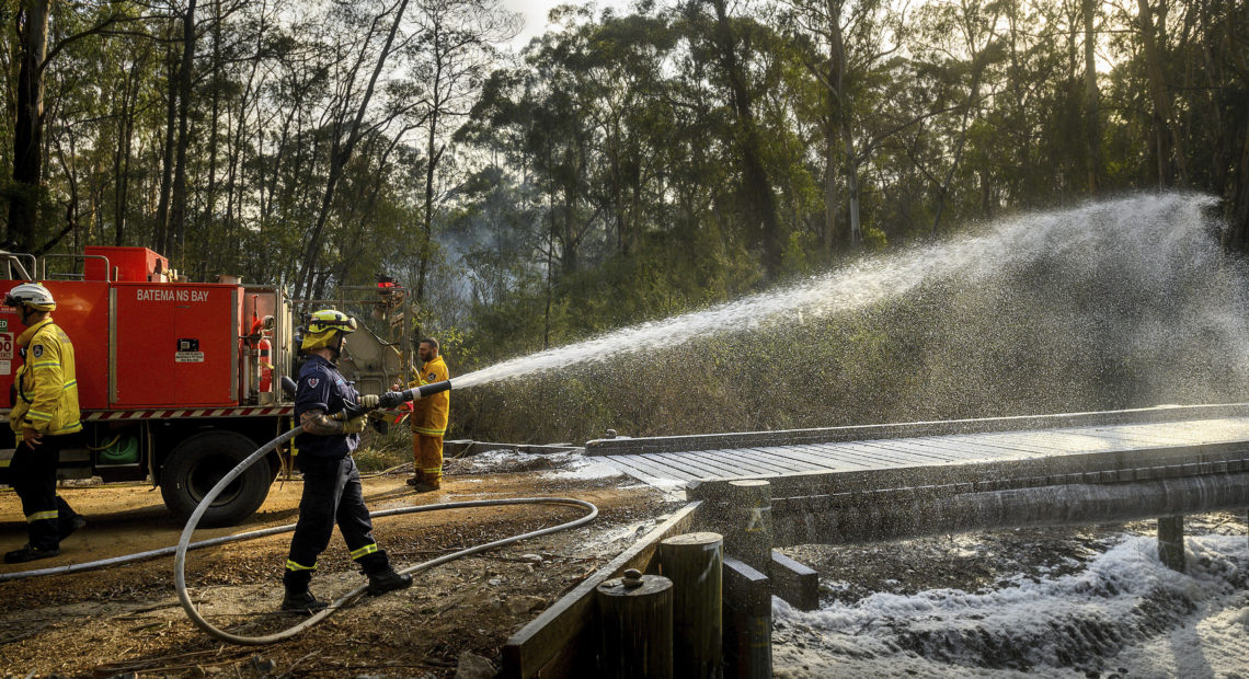 A firefighter coats a bridge with foam as a bushfire burns near Moruya, New South Wales, Australia, on Jan. 25. Wildfires destroyed more than 3,000 homes and razed more nearly 11 million hectares since the summer fires began. Noah Berger/AP