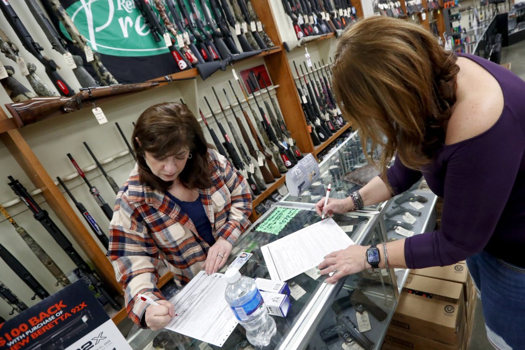 Andrea Schry (right) fills out the buyer's part of legal forms to buy a handgun as shop worker Missy Morosky fills out the vendor's parts after Dukes Sport Shop in New Castle, Pa., reopened on Wednesday. Keith Srakocic/AP
