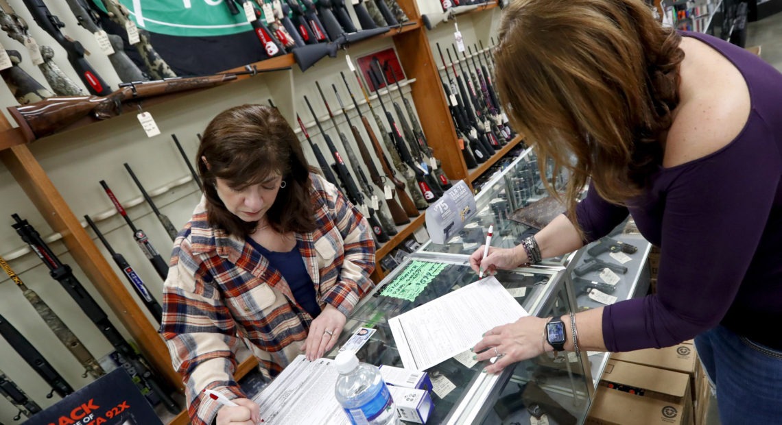Andrea Schry (right) fills out the buyer's part of legal forms to buy a handgun as shop worker Missy Morosky fills out the vendor's parts after Dukes Sport Shop in New Castle, Pa., reopened on Wednesday. Keith Srakocic/AP