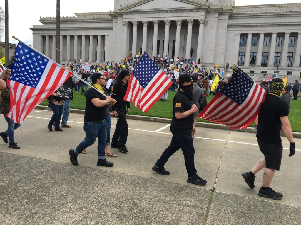 Protesters in the black and yellow shirts worn by the Proud Boys march in Olympia on April 19, 2020. CREDIT: Will James/KNKX