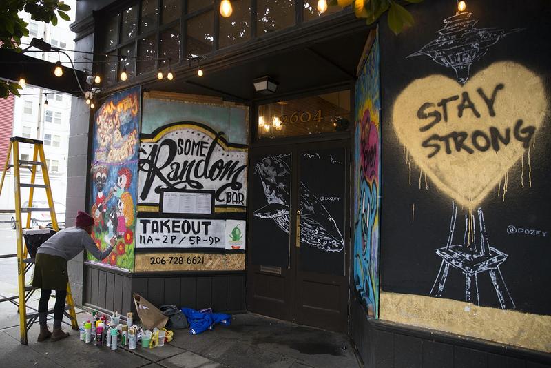 Shavonne Maes paints a mural onto the boarded up facade of Some Random Bar on March 26, 2020, in Seattle.