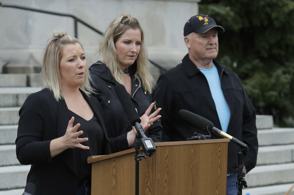 Tonya Fenton, left, stands with her sister, Trisha Woods and their father, Fred Binschus, April 23, 2020, outside the Temple of Justice at the Capitol in Olympia, Wash. Fenton's mother Julie was murdered in 2008 and the three joined others in speaking out against the release of prison inmates due to the spread of the coronavirus as Washington state Supreme Court justices heard oral arguments inside. CREDIT: Ted S. Warren/AP