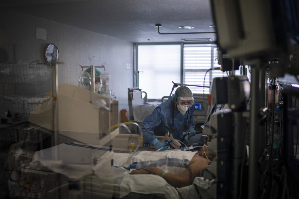 Health care workers assist a COVID-19 patient in Spain. Some evidence from Europe and China suggests an overzealous immune response may be contributing to the severe illness in some patients. CREDIT: Felipe Dana/AP