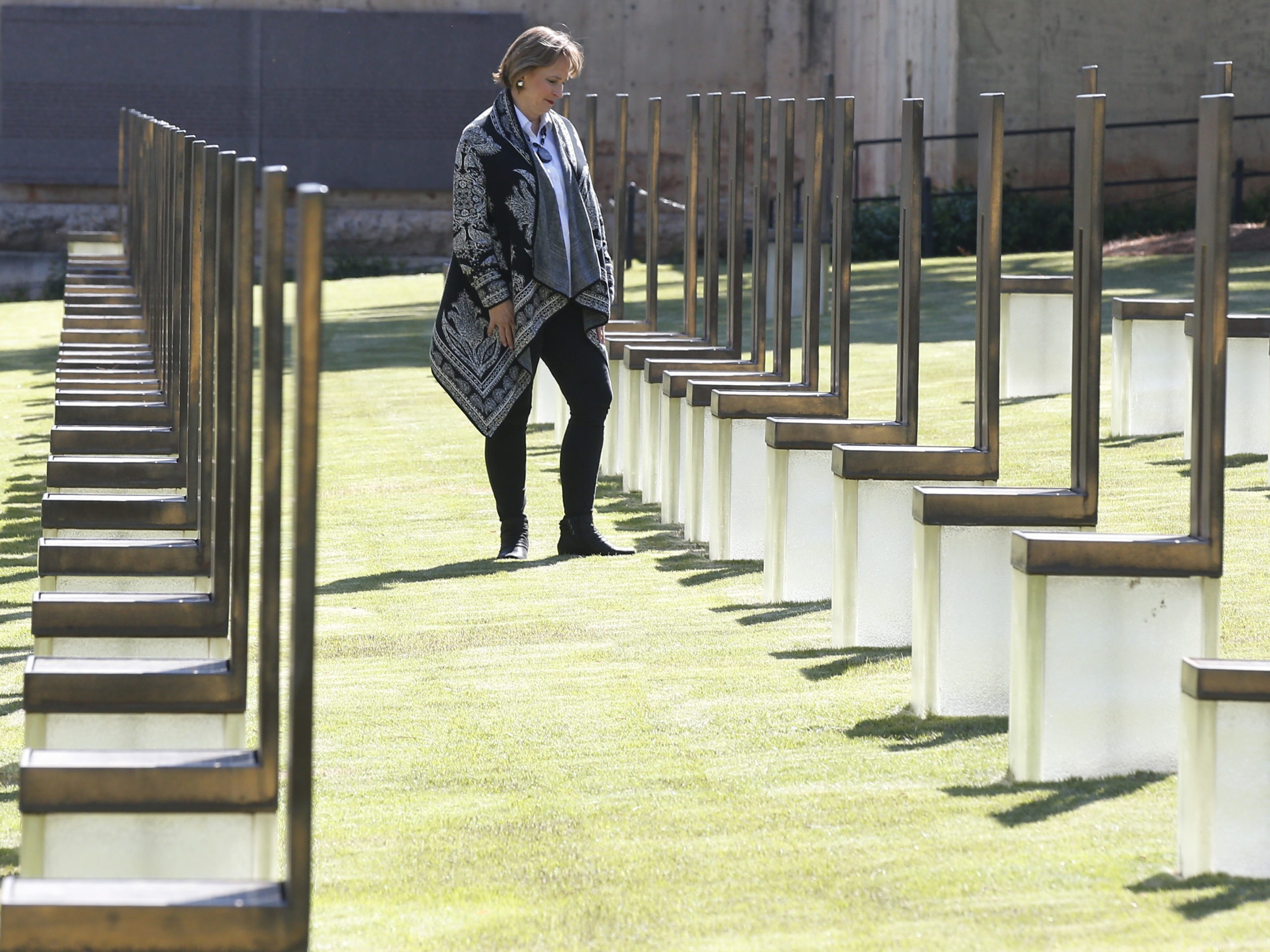 Lynne Gist stands at her sister's chair in the Field of Empty Chairs at the Oklahoma City National Memorial and Museum