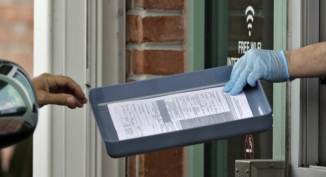 A County Library employee hands unemployment paperwork to residents in Tampa, Fla.