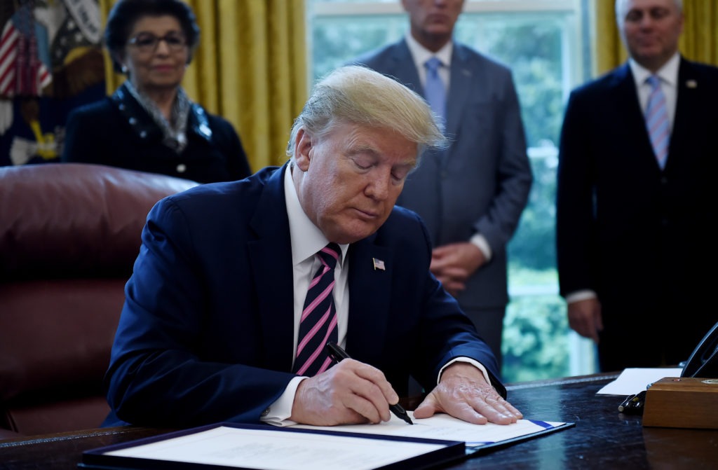 President Trump a new coronavirus economic aid package, largely targeted to support small businesses, in the Oval Office on Friday. CREDIT: Olivier Douliery/AFP via Getty Images