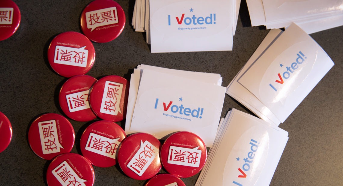 Voting pins and stickers lie next to a ballot box earlier this year during early voting at the King County Elections