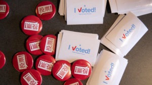 Voting pins and stickers lie next to a ballot box earlier this year during early voting at the King County Elections