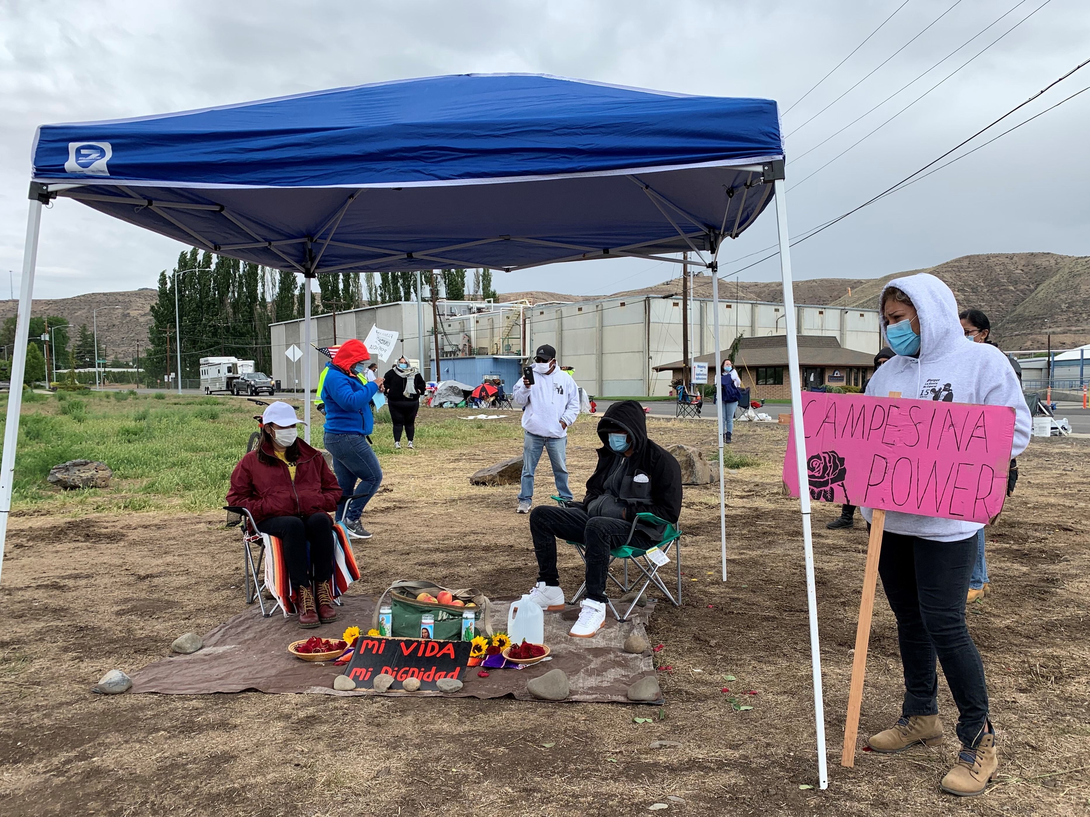 Elvira Medina and Cesar Gonzalez sit by a makeshift altar Tuesday, May 19 after launching a hunger strike, protesting stalled negotiations with their employer Allan Brothers Fruit and demanding a $2 dollar an hour increase in pay. CREDIT: Enrique Pérez de la Rosa/NWPB