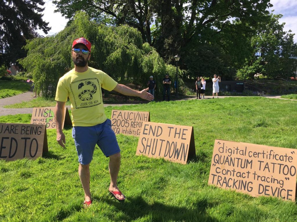 This man, who would not give his name, set up cardboard signs on the Capitol lawn warning of government tracking to stem the spread of COVID-19. CREDIT: Austin Jenkins/N3