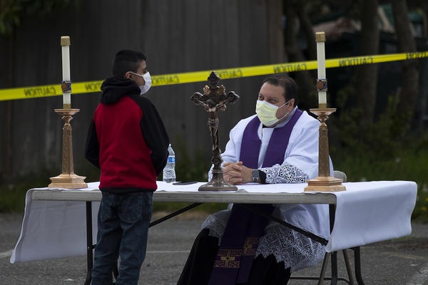 Father Jose Alvarez, right, during walk and drive through confessions on Friday, April 24, 2020, in the parking lot at Holy Roman Catholic Church in White Center. CREDIT: Megan Farmer/KUOW
