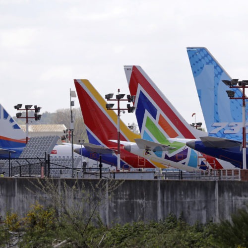 A line of Boeing 737 MAX jets sit parked on the airfield adjacent to a Boeing production plant last month in Renton, Wash. Boeing now says it is cutting thousands of jobs