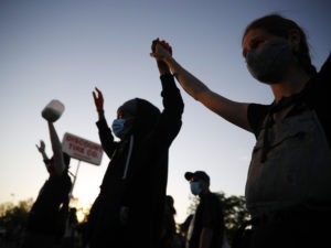 Demonstrators join hands on Thursday, May 28, 2020, in St. Paul, Minn. Protests over the death of George Floyd, a black man who died in police custody, broke out in Minneapolis for a third straight night.