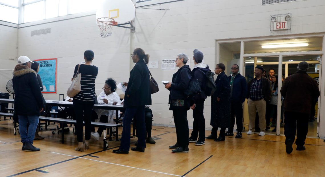 People stand in line at a Detroit polling place during Michigan's March 10 presidential primary. Because of the pandemic, the state's top election official is sending absentee ballot applications to every registered voter for August and November elections.