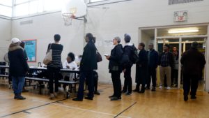 People stand in line at a Detroit polling place during Michigan's March 10 presidential primary. Because of the pandemic, the state's top election official is sending absentee ballot applications to every registered voter for August and November elections.
