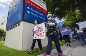 Health care workers hold a placard that says From Heroes to Zeroes during a protest against hospital under-staffing and insufficient personal protective equipment for doctors and nurses treating COVID-19 patients amid the coronavirus pandemic. The protest took place outside Saint Joseph Medical Center hospital in Burbank, Calif. on May 19.