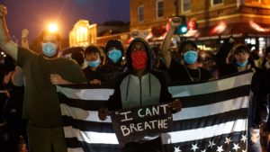 Protesters gather Tuesday near where Floyd died in police custody in Minneapolis. One of them displays Floyd's final words, recalling those made famous by Eric Garner when he died in 2014 in New York City.