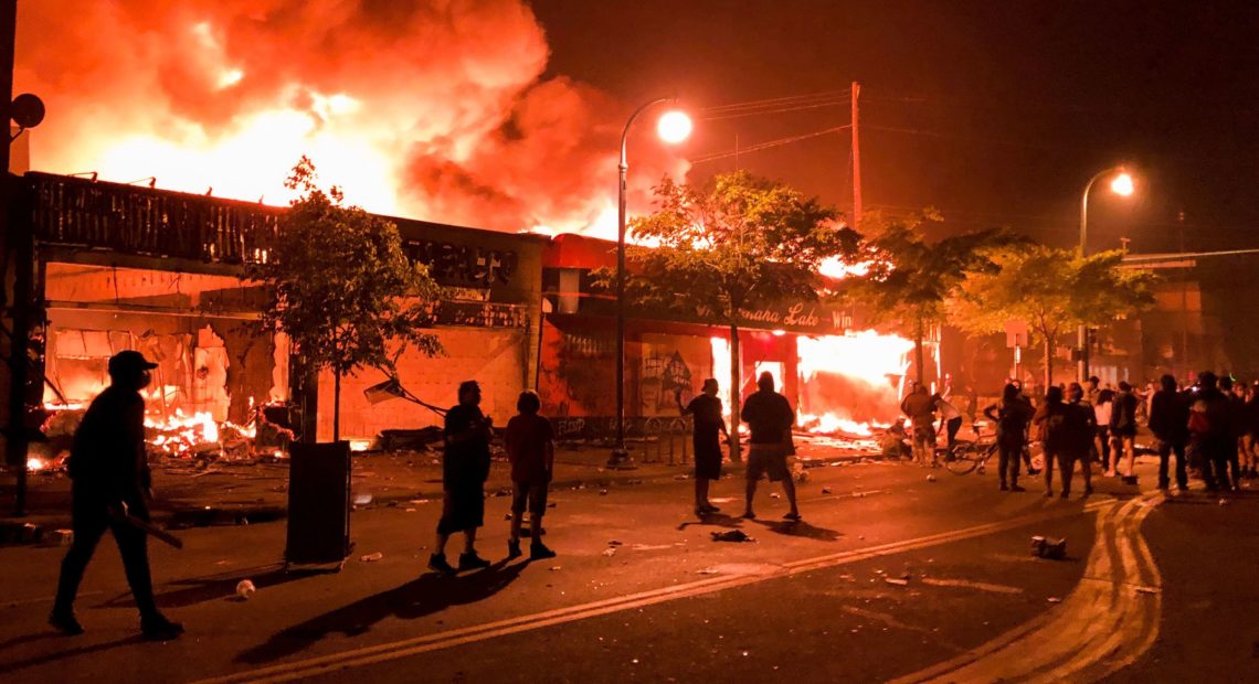 Flames rise from a liquor store and shops near the 3rd Police Precinct in Minneapolis on Thursday , during a protest over the death of George Floyd.