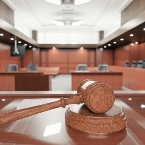 Interior of an empty courtroom with gavel and sounding block on the desk.