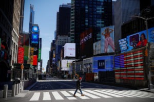 A man wearing a protective face mask crosses 7th Avenue in a nearly deserted Times Square in Manhattan during the outbreak of the coronavirus disease.