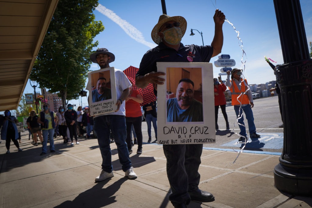 Farmworkers in Yakima’s fruit-packing industry walked off production lines in May and went on strike, demanding more protections against the coronavirus pandemic. Above, Emmanuel Anguiano-Mendoza (left) and Agustin López hold posters featuring David Cruz, a worker who died on May 30. CREDIT: Enrique Pérez de la Rosa/NWPB