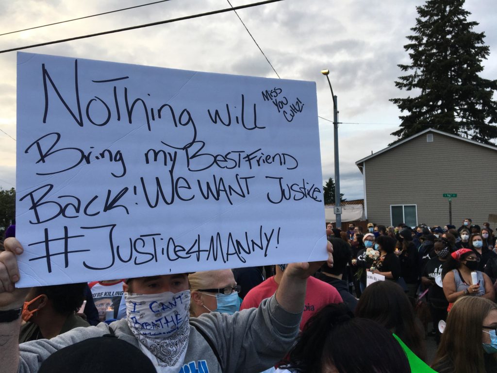 Manuel Ellis' friend holds up a sign demanding justice. Ellis died March 3 in the custody of Tacoma police. The officers invovled have been placed on leave, after a medical examiner's report was made public.